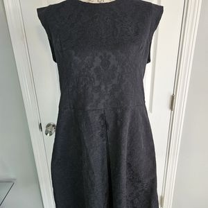 Laundry dress features black brocade material, front pleat, and pockets